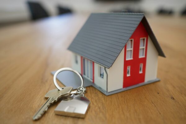 A pair of silver keys sits next to a small model house